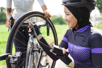 Frau pumpt das Fahrrad mit einer elektrischen Fahrradpumpe auf