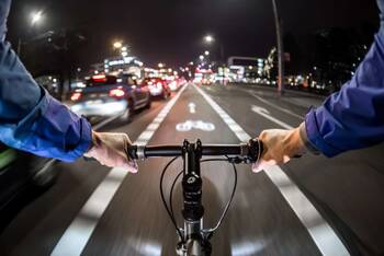 Radfahrer bei Dunkelheit im Stadtverkehr auf Fahrradweg
