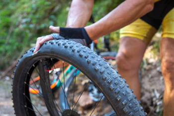Mann prüft Druck von Fahrradschlauch mit Händen