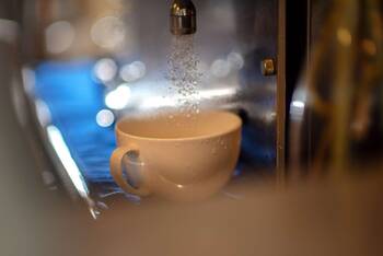 Wsser beim Kaffeemaschinenreinigungsprozes fließt in Tasse