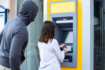 Mann beobachtet PIN Eingabe am Bankautomaten