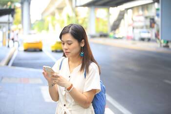 Frau schaut auf Smartphone an öffentlichem Ort