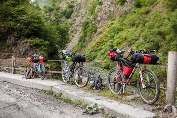 Drei Fahrräder in bergigem Gelände, die mit rot-schwarzen Bikepacking-Taschen versehen sind