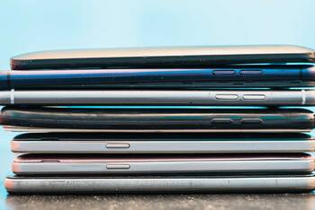 Viele Smartphones liegen aufeinander vor blauem Hintergrund
