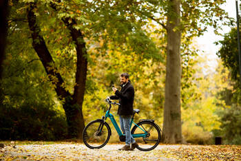 Mann steht neben E-Bike im Stadtpark