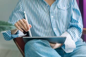 Person im Hemd und Jeans nutzt iPad mit Apple Pencil