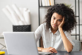Eine Frau schaut frustiert auf ihren Laptop