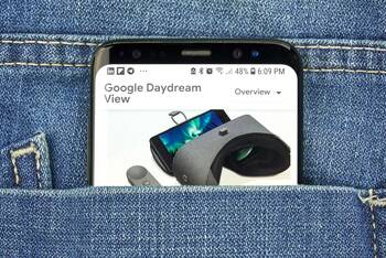 Schwarzes Smartphone in einer Hosentasche. Auf dem Bildschirm wird ein Bild der Google Daydream Brille gezeigt. 