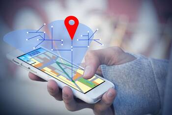 Composing aus Smartphone in der Hand eines Nutzers und grafischen Standortkoordinaten