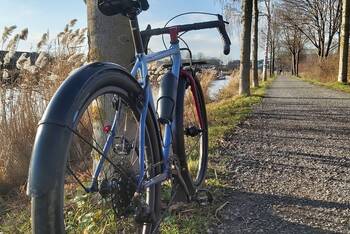 Ein Gravel Bike von hinten fotografiert auf einem Schotterweg bei sonnigem Winterwetter..