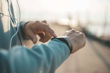Person Outdoor tippt mit einer Hand auf Smartwatch an anderem Handgelenk