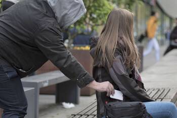 Mann mit Kapuze klaut unbemerkt Smartphone aus der Jackentasche einer Frau