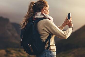 Frau macht Kamera mit Handy in Berglandschaft
