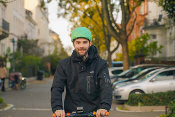 Mann auf E-Scooter fährt mit Inflabi Helm.
