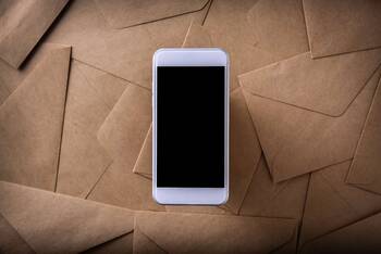 Smartphone liegt auf braunen Briefumschlägen