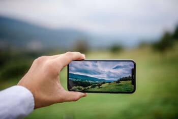 jemand fotografiert mit einem iPhone eine Landschaft