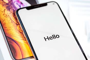ein iPhone liegt auf dem Tisch und zeigt "Hello" an