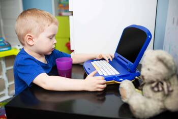 Ein kleiner Junge sitzt vor einem Kinder-Computer