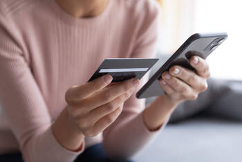 Frau tippt Kreditkartendaten in Handy ein