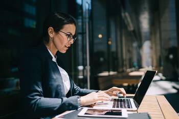 Frau in Business Klamotten sitzt vor Laptop