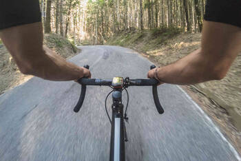 Mann auf Rennrad fährt auf Straße durch Wald.