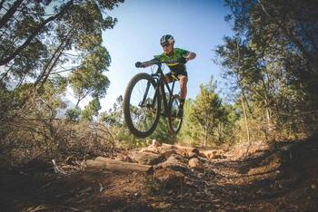 Mountainbiker springt mit Mountainbike durch den Wald