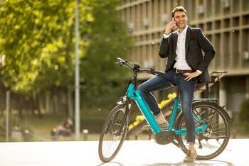 Mann steht mit seinem Fahrrad in der Stadt