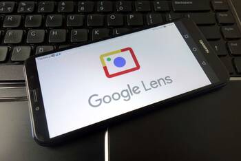 Auf Tastatur liegendes Smartphone mit Google Lens Applikation