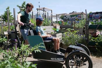 Mann mit Kind und Lastenrad in einem Feld