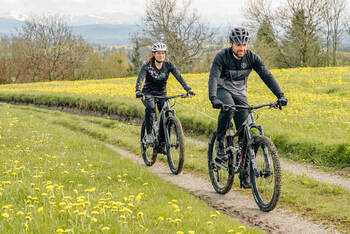 Mann auf Fahrrad schleppt Frau auf Fahrrad mit Seil ab.