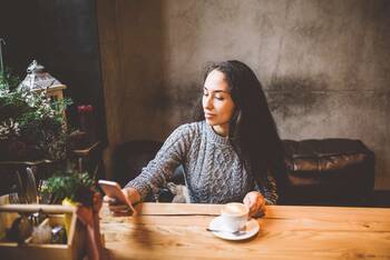Frau in Café schaut auf Smartphone