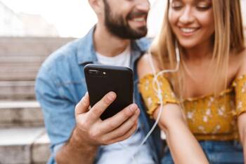 Pärchen hören mit Handy über Kopfhörer Musik