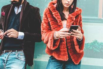 Mann und Frau in Designer-Klamotten bedienen ihr ihr Smartphone
