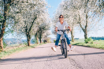 Frau fährt lachend auf dem Fahrrad im Frühling