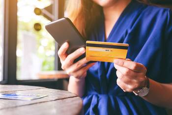 Frau tippt Kreditkarten-Daten in Smartphone ein
