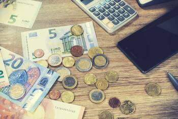 Bargeld, Taschenrechner und Smartphone liegen auf Tisch 