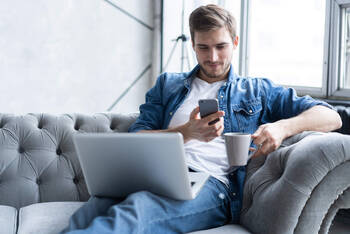 Mann sitzt auf Sofa und benutzt Online Banking