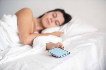 Schlafende Frau hält Smartphone in der Hand