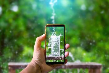 Smartphone mit Wasserglas-Motiv hinter der Handykamera