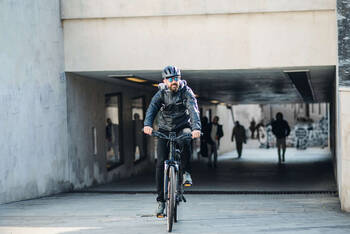 Mann mit Helm fährt mit E-Bike durch Stadt.