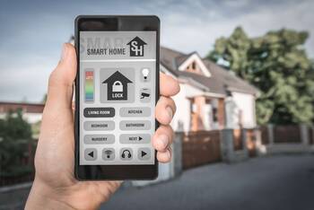 Geöffnete Smart Home Anwendung auf dem Smartphone mit einem Haus im Hintergrund