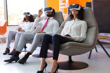 Drei Personen sitzen mit VR-Brille auf Sesseln