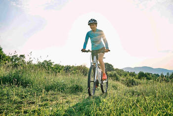 Frau fährt mit Mountainbike über Wiese.