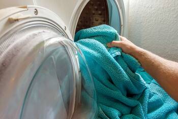 Person holt Handtücher aus der Waschmaschine