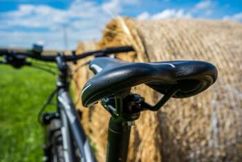 Foto eines Fahrrads, welches an einem Strohballen lehnt, mit Fokus auf den Fahrradsattel