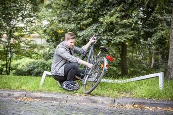 Mann untersucht Fahrrad am Wegrand auf Beschädigungen