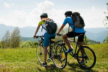 Mann und Frau auf Fahrrad schauen in Bergland.