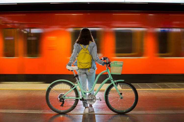 Frau sitzt auf Ihrem Fahrrad und wartet auf die Bahn.