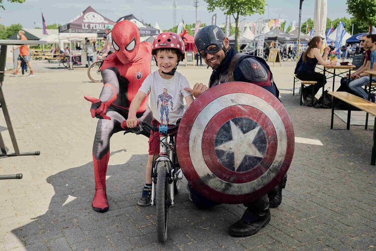 Ein Radfahrerkind zwischen zwei Superhelden