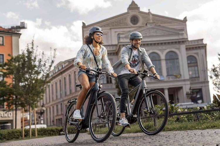 zwei Personen mit Helm fahren Fahrrad.